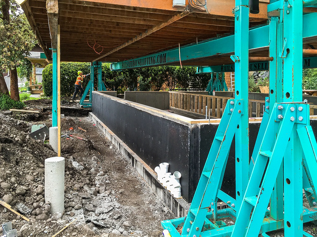 Wood-frame house lifted above existing foundation